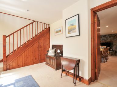A hallway with a staircase and decorative furniture at Rosewin Farmhouse near St Minver