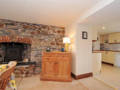 A living room with a fireplace and cabinet at Rosewin Farmhouse near St Minver