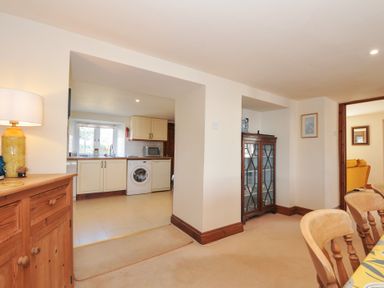 A dining room with a sideboard and a view into the kitchen at Rosewin Farmhouse near St Minver