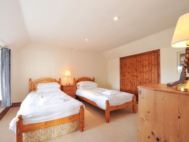 A bedroom with two single beds and a bedside table at Rosewin Farmhouse near St Minver