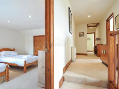 A bedroom with a bed and an adjoining hallway at Rosewin Farmhouse near St Minver