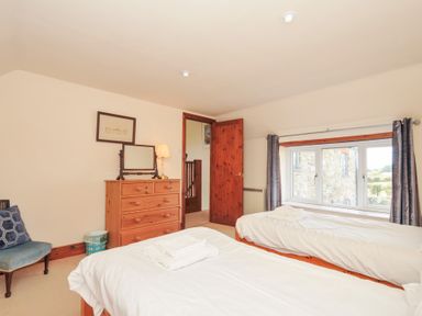 A bedroom with two beds and a dressing table at Rosewin Farmhouse near St Minver
