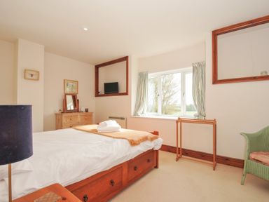 A bedroom with a bed, dresser, and television at Rosewin Farmhouse near St Minver