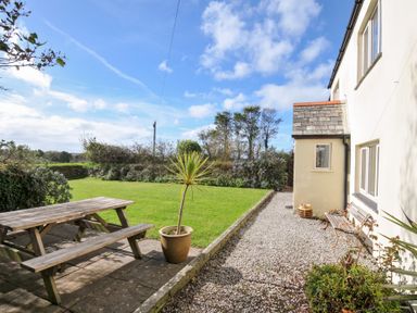 A garden with a picnic table and flower planter at Rosewin Farmhouse near St Minver