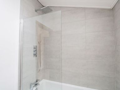 A shower area with glass panel and bathtub at Easedale Lodge, Waterside Wood 2, White Cross Bay near Windermere
