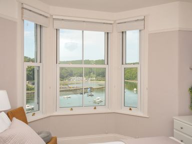 A bedroom with a view of boats on the water at Overdale in Looe