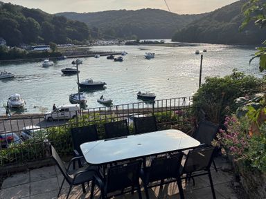 A table and chairs overlooking water with boats at Overdale in Looe