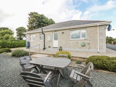 A house with a table and chairs in the garden at Dunbrody Dreams
