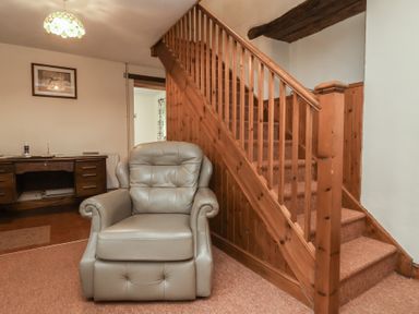 A living room with a chair and staircase at Denhill Cottage