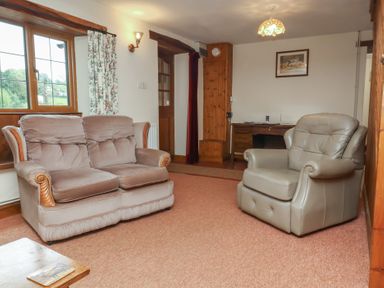 A living room with a sofa and armchair at Denhill Cottage