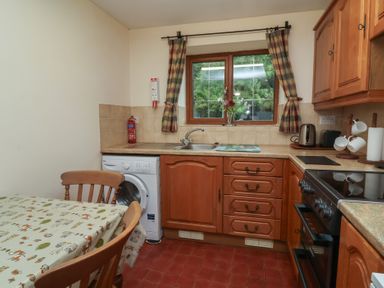 A kitchen with a table and washing machine at Denhill Cottage in 