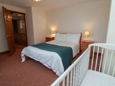 A bedroom with a bed and crib at Denhill Cottage