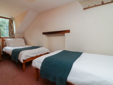A bedroom with two beds and a window at Denhill Cottage 