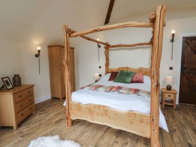 A bedroom with a four-poster bed and nightstands at Yr Awen in Lampeter