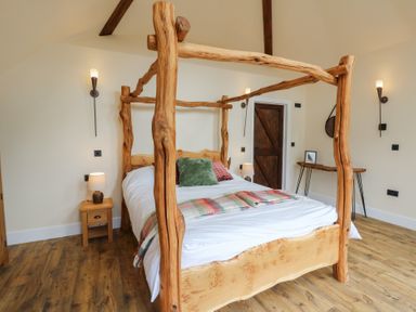 A bedroom with a wooden bed and bedside table at Yr Awen in Lampeter