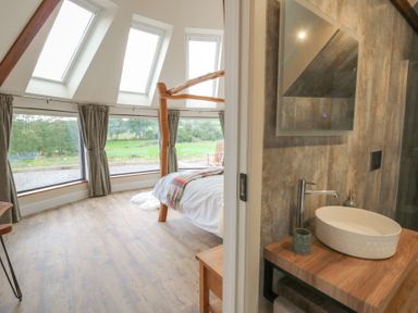A bedroom with a bed and a bathroom sink at Yr Awen in Lampeter