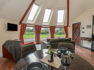 A living room with a dining table and wine at Y Cwlwm Lampeter