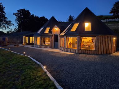 A house with illuminated windows at Y Cwlwm - The Celtic Knot near Lampeter