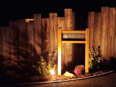 A sign with the name MAES CELT illuminated at night near Lampeter