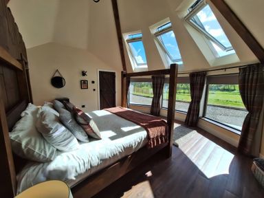 A bedroom with a bed and windows at Y Cwlwm - The Celtic Knot near Lampeter