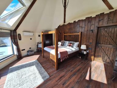 A bedroom with a wooden bed and window at Y Cwlwm - The Celtic Knot Near Lampeter