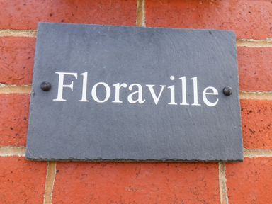 A slate sign with the name Floraville on a brick wall