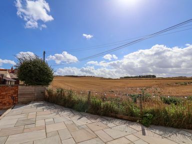 An outdoor area with a stone patio overlooking an open field at Floraville