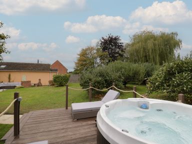 A garden with a hot tub and sun lounger at Harran in Pershore