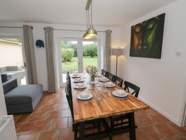 A dining room with a wooden table set for a meal at Harran in Pershore