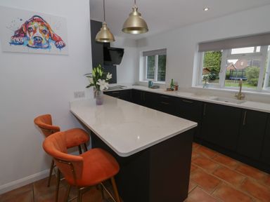 A kitchen with a bar stools and kitchen island at Harran in Pershore