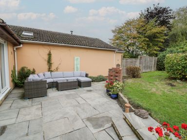 A garden with a sectional sofa and planters at Harran in Pershore