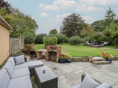 A garden with a sofa and barbecue area at Harran in Pershore