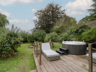 A garden with a hot tub and lounge chair at Harran in Pershore
