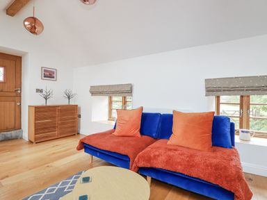 A living room with a blue sofa and a wooden sideboard at The Old Dairy in 