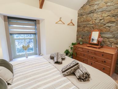 A bedroom with a bed and a dresser at Penally Mews St Dogmaels