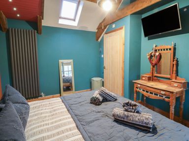 A bedroom with a bed and a dressing table at Penally Mews St Dogmaels