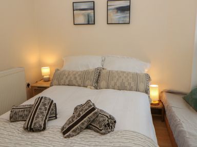 A bedroom with a bed and bedside table at Penally Mews St Dogmaels
