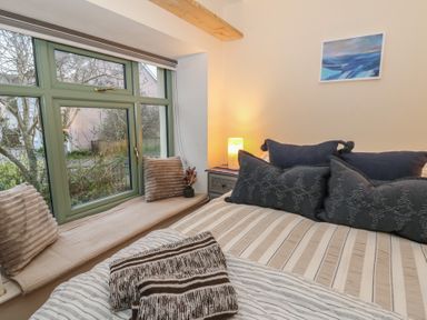 A bedroom with a bed and window at Penally Mews St Dogmaels