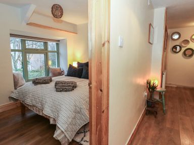 A bedroom with a bed and windows at Penally Mews in St Dogmaels