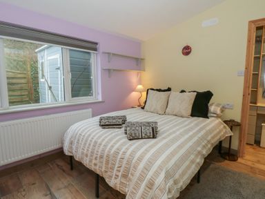 A bedroom with a double bed and shelves at Penally Mews in St Dogmaels