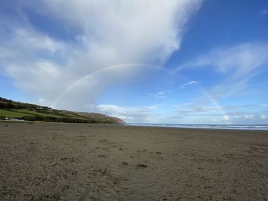 A beach with a rainbow in the sky at Penally Mews St Dogmaels