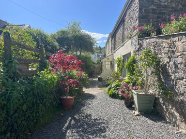 An outdoor area with a gravel path and flower pots at Penally Mews in St Dogmaels