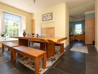 A dining room with a wooden table and benches at The Old Vicarage in St Issey