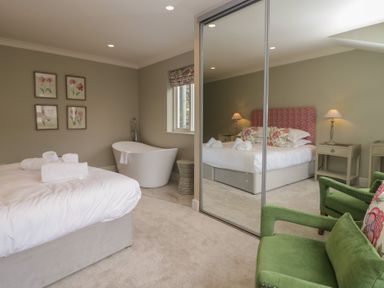 A bedroom with a bed, bathtub, and green chair at The Boundary in Windermere