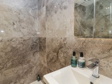 A sink with soap dispensers and tiles in the bathroom at The Boundary in Windermere