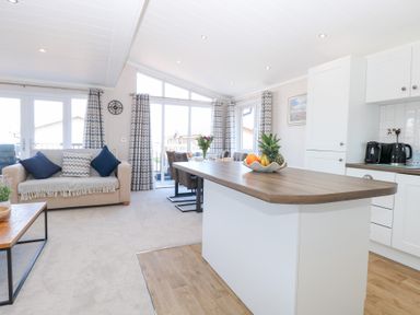 A living room with a sofa and dining table at Sandy Snug in Bacton
