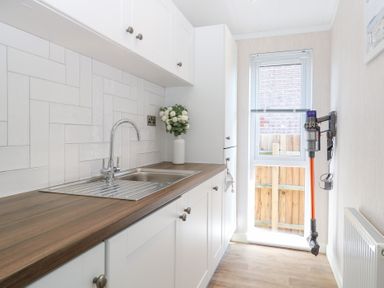A laundry room with a sink and cabinets at Sandy Snug in Bacton