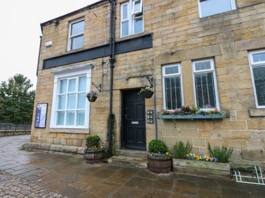 A front view of a stone building with a door and windows at The Railway Apartment in Hexham