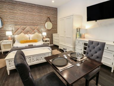 A bedroom with a dining area and a television at The Railway Apartment in Hexham