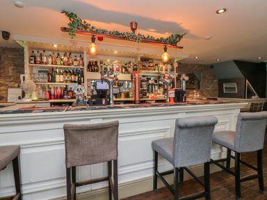 A bar with shelves of drinks and seating at The Railway Apartment in Hexham